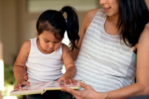 Young ethnic mother looking at a book with her daughter